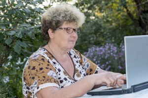 elderly woman working on  computer in the garden